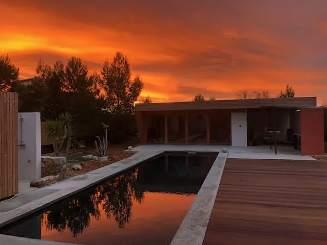 Orange sunset sky reflected in the pool at 4U Bed&Spa, with the pool house behind