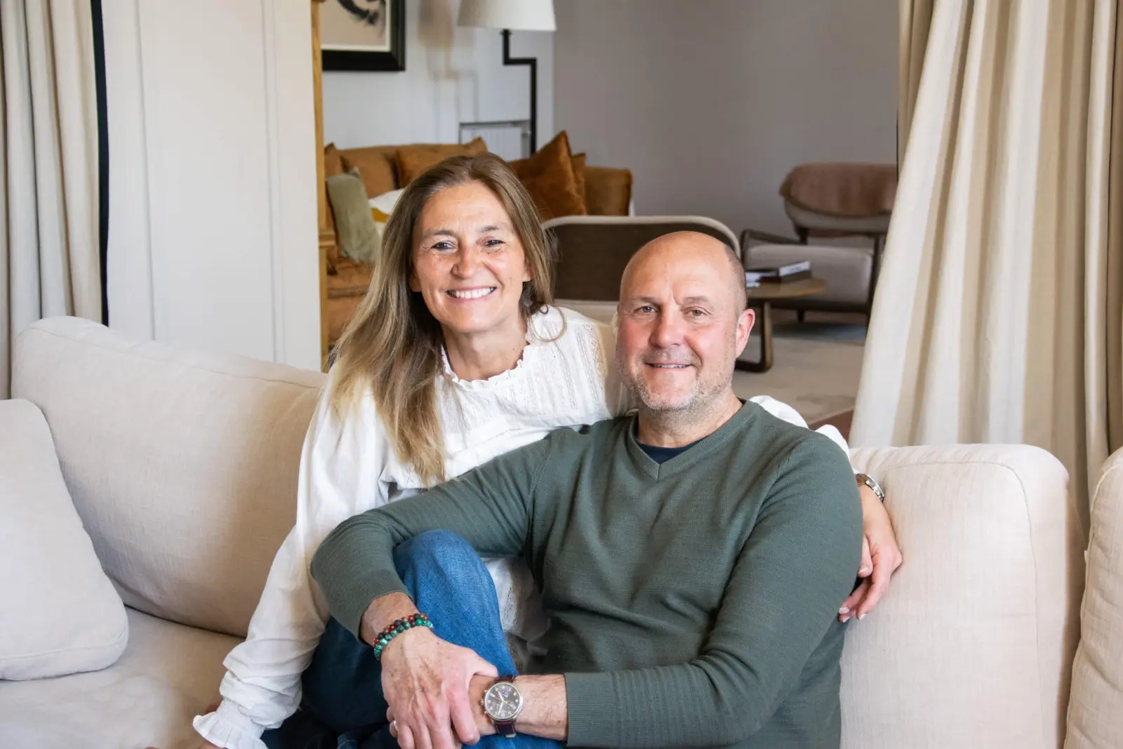 Claire and Phil, hosts of La Bastide de Margaux, smiling on a pale sofa