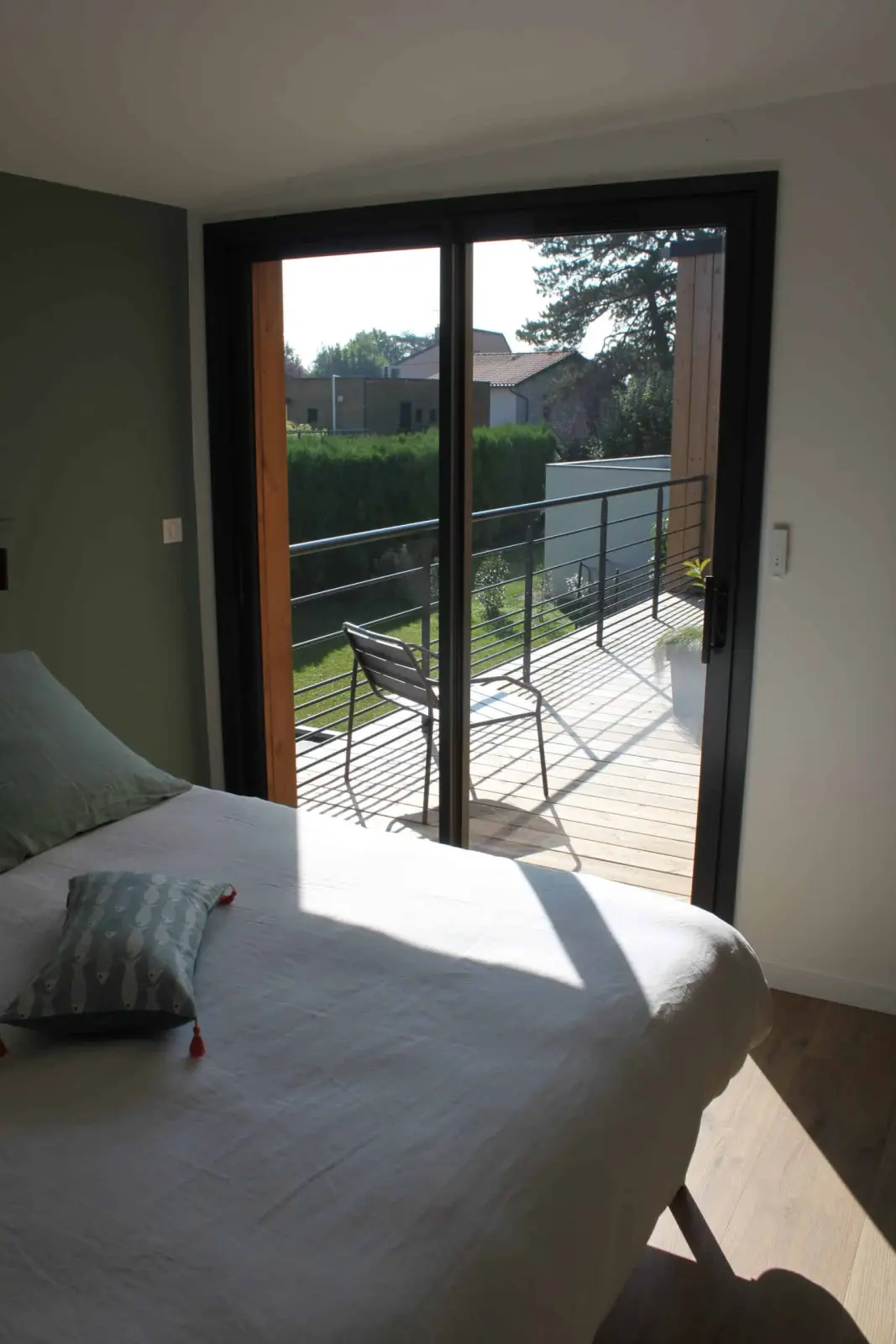 Bedroom at Bread et Couette with a bed and a sliding glass door opening onto a wooden balcony with a chair