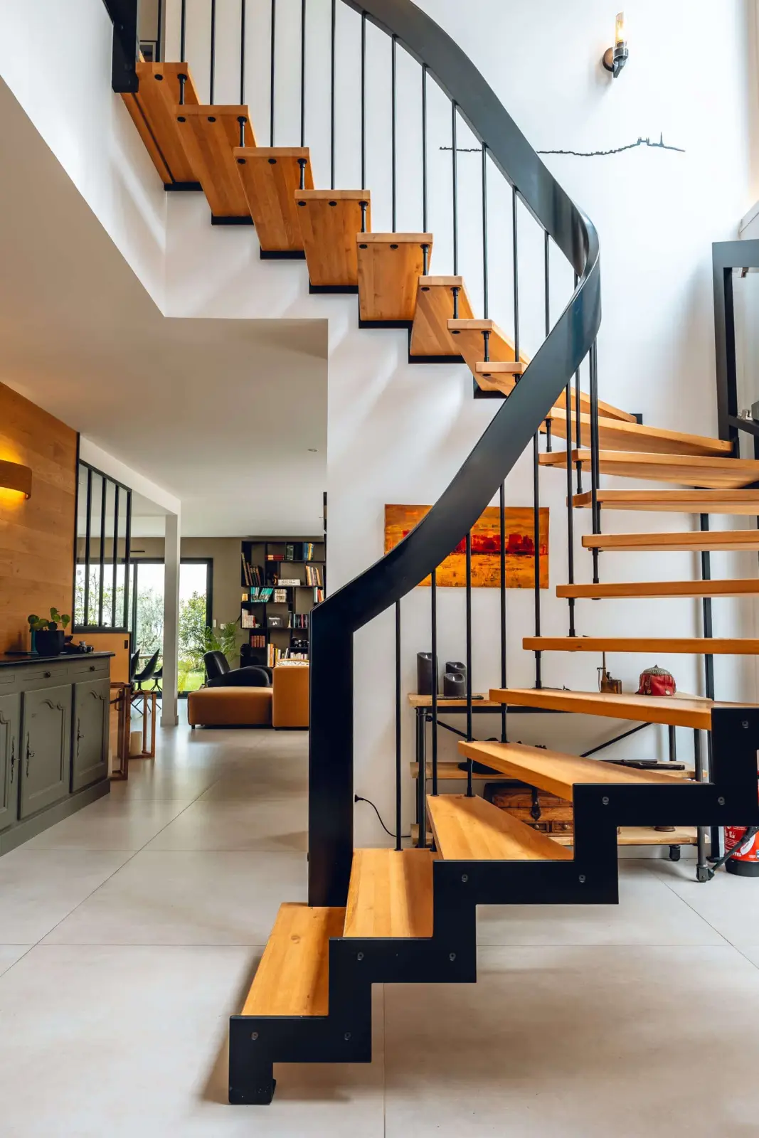 Spiral staircase with wooden treads and black metal handrail leading to the living area at Bread et Couette