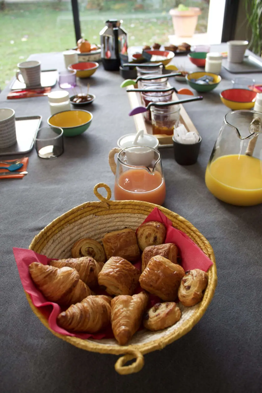 Breakfast at Bread et Couette: basket of croissants and pains au chocolat, juices and colourful bowls