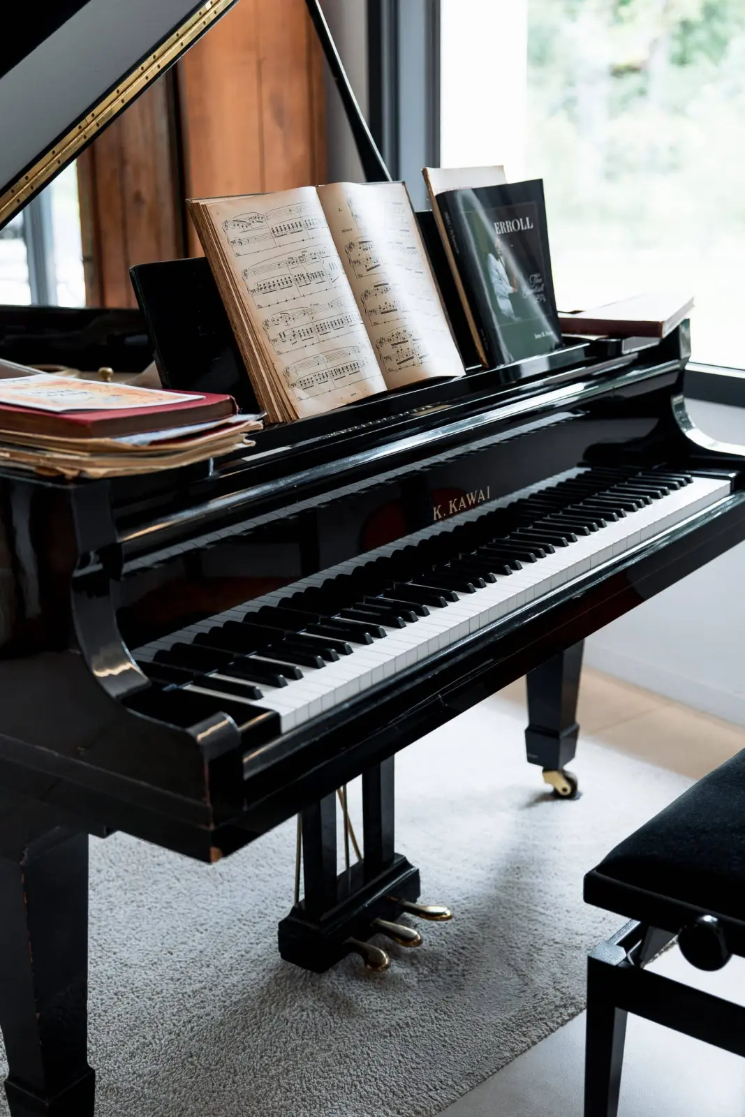 Black grand piano with open sheet music in front of a large window, at Bread et Couette