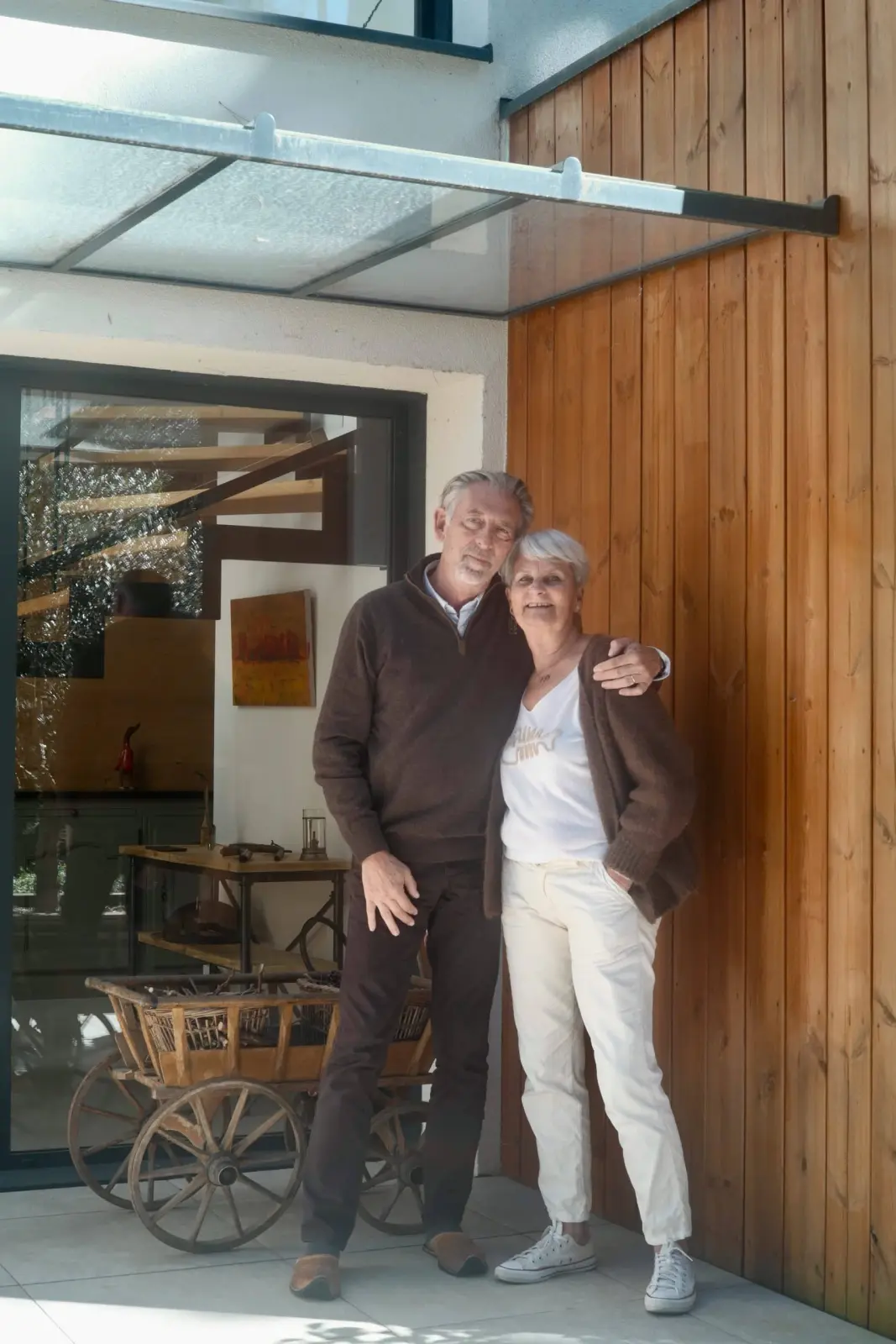 Sophie and Antoine, hosts of Bread et Couette, in front of the glazed, wood-clad entrance of the house