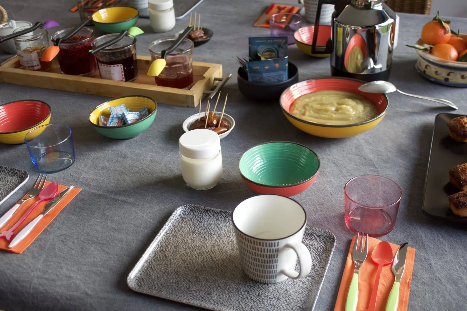 Breakfast table at Bread et Couette with colourful bowls, jams, fruit compote and mandarins