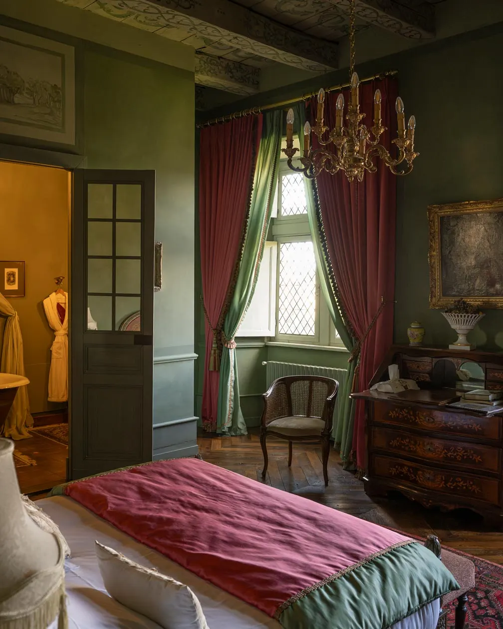 Green-walled bedroom at Château de Canac with gilt chandelier, red curtains, antique chest and leaded windows