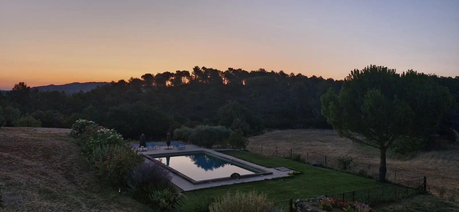 Pool at Chut ! c'est ici at dusk, orange sky above the pines and the meadow