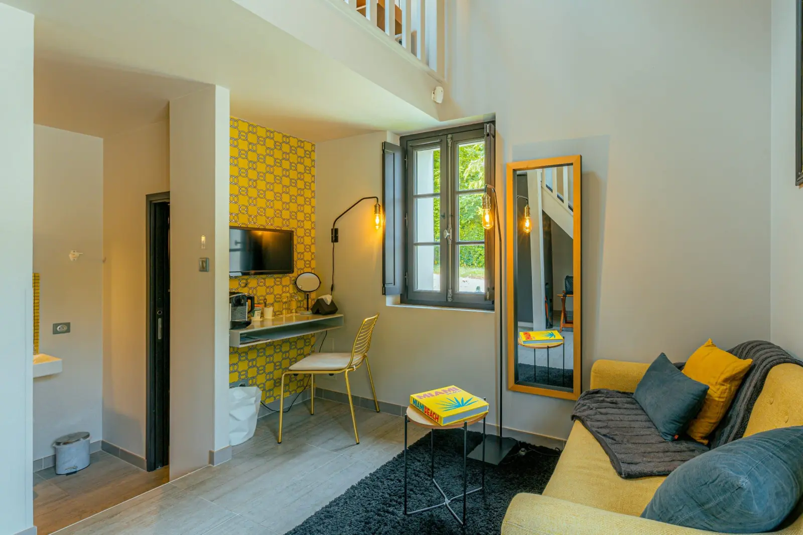 Côté Vignes room at Clos Marcamps with yellow tiled wall, desk corner, yellow sofa and gilt mirror