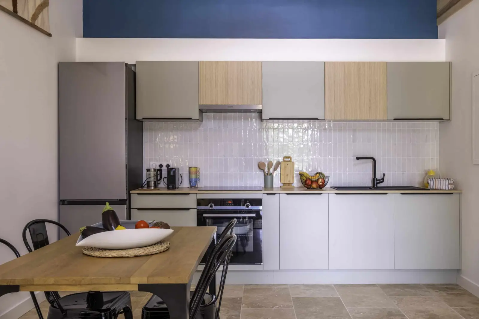 Fitted kitchen in the Clos Marcamps duplex, grey and wood units, white splashback and wooden table