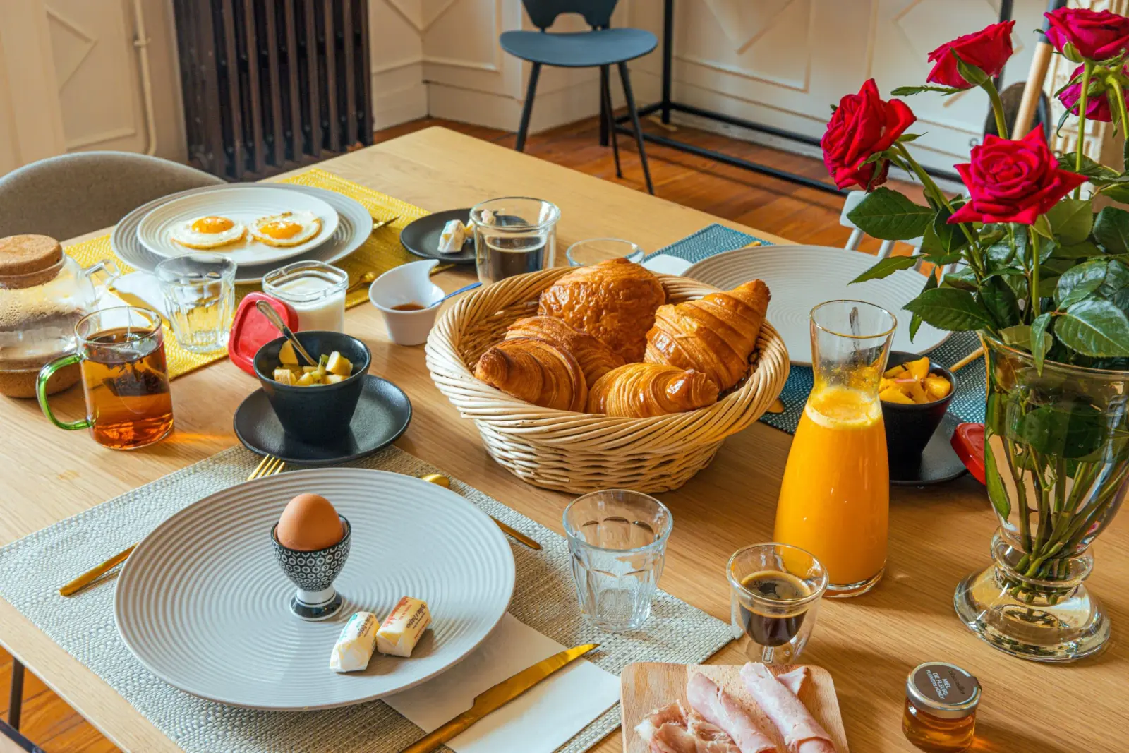Breakfast at Clos Marcamps: croissants, fried eggs, a boiled egg, orange juice and red roses