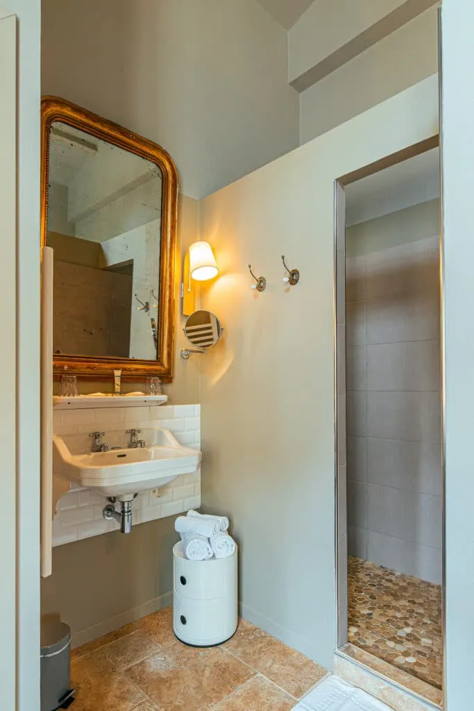 Côté Jardin bathroom at Clos Marcamps with washbasin, gilt mirror, walk-in shower and stone floor