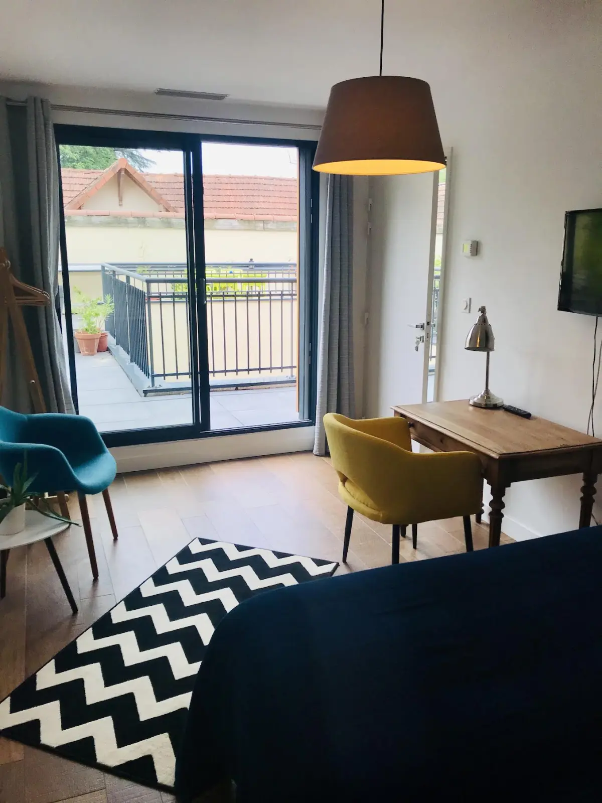 Gamboa room at Effet Lodge with a glass door onto a terrace, wooden desk, yellow and blue armchairs