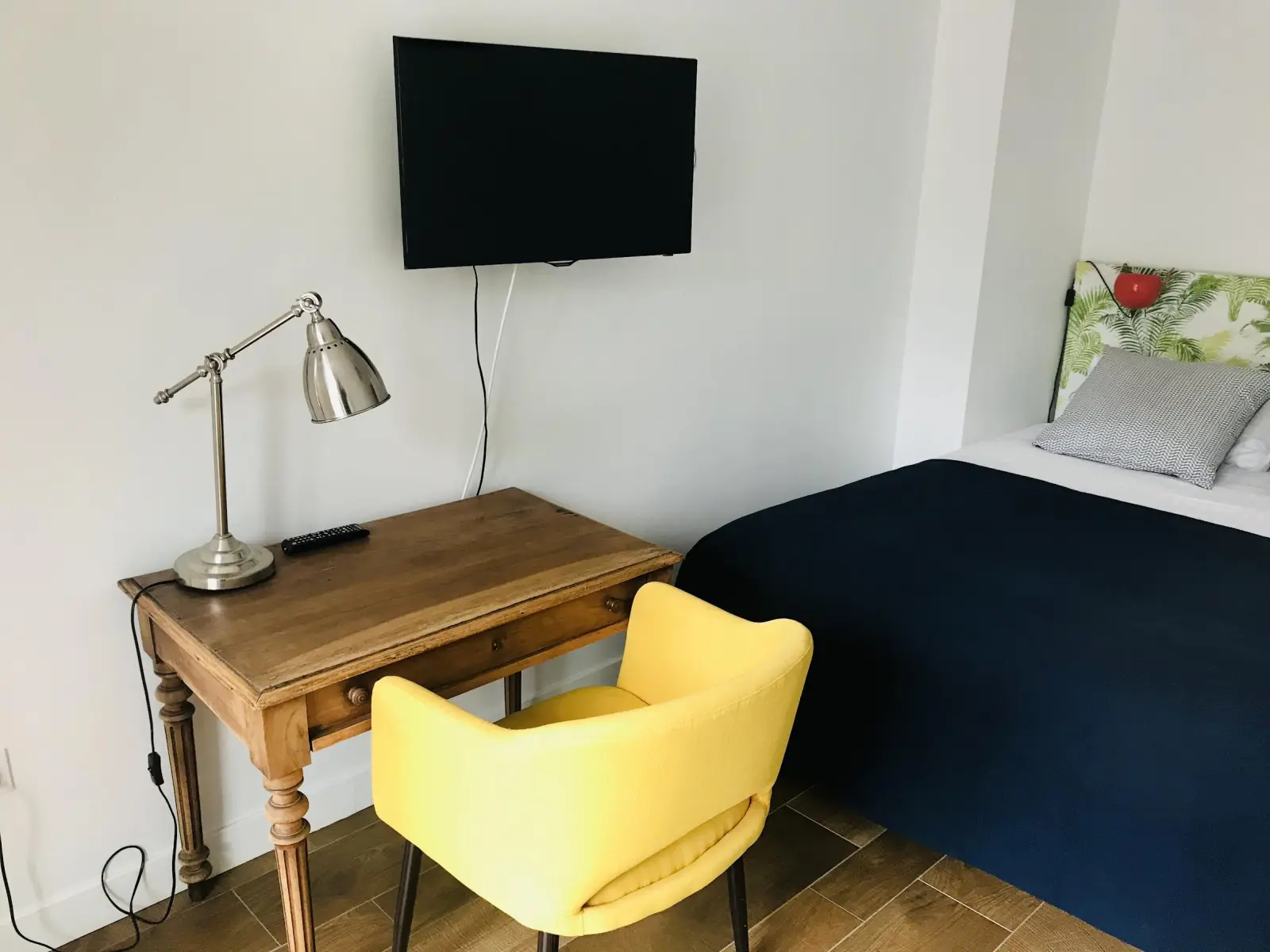 Desk corner in the Gamboa room at Effet Lodge: wooden desk, lamp, yellow chair and wall-mounted TV