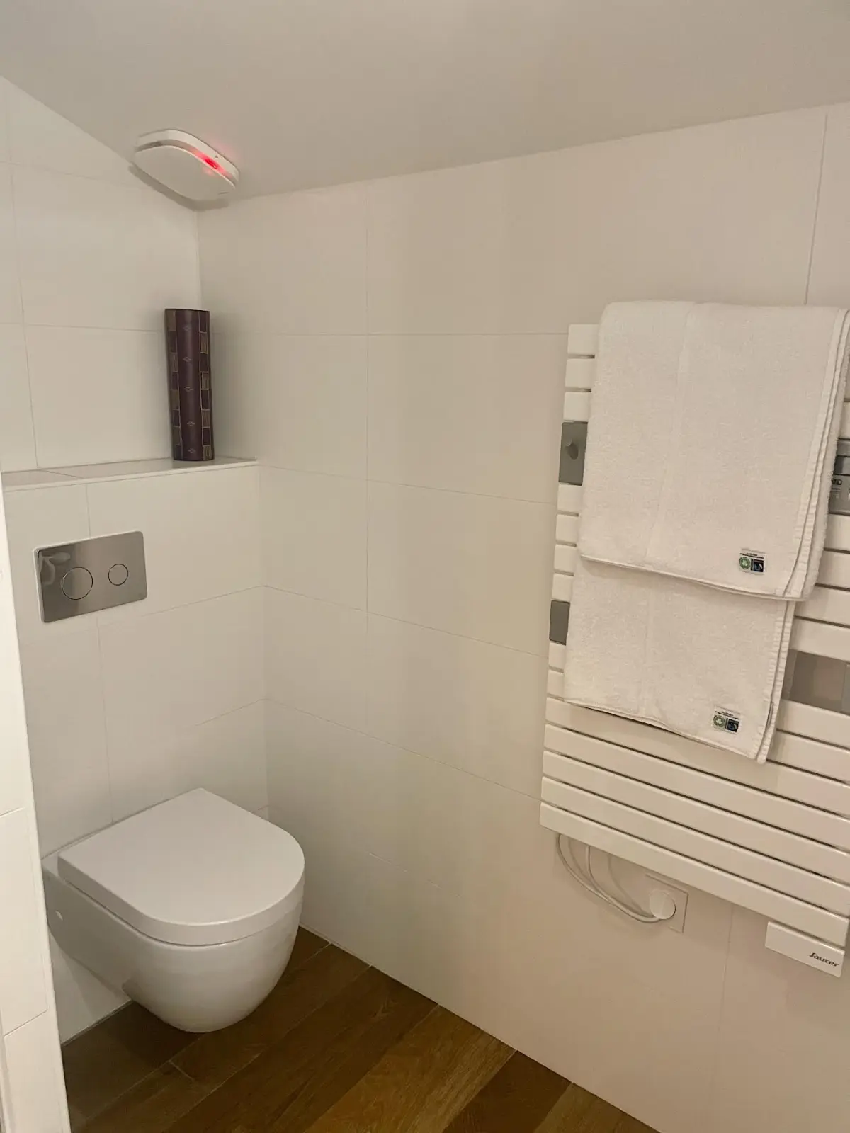 Wall-hung WC and heated towel rail with white towels in the Hermosa bathroom at Effet Lodge