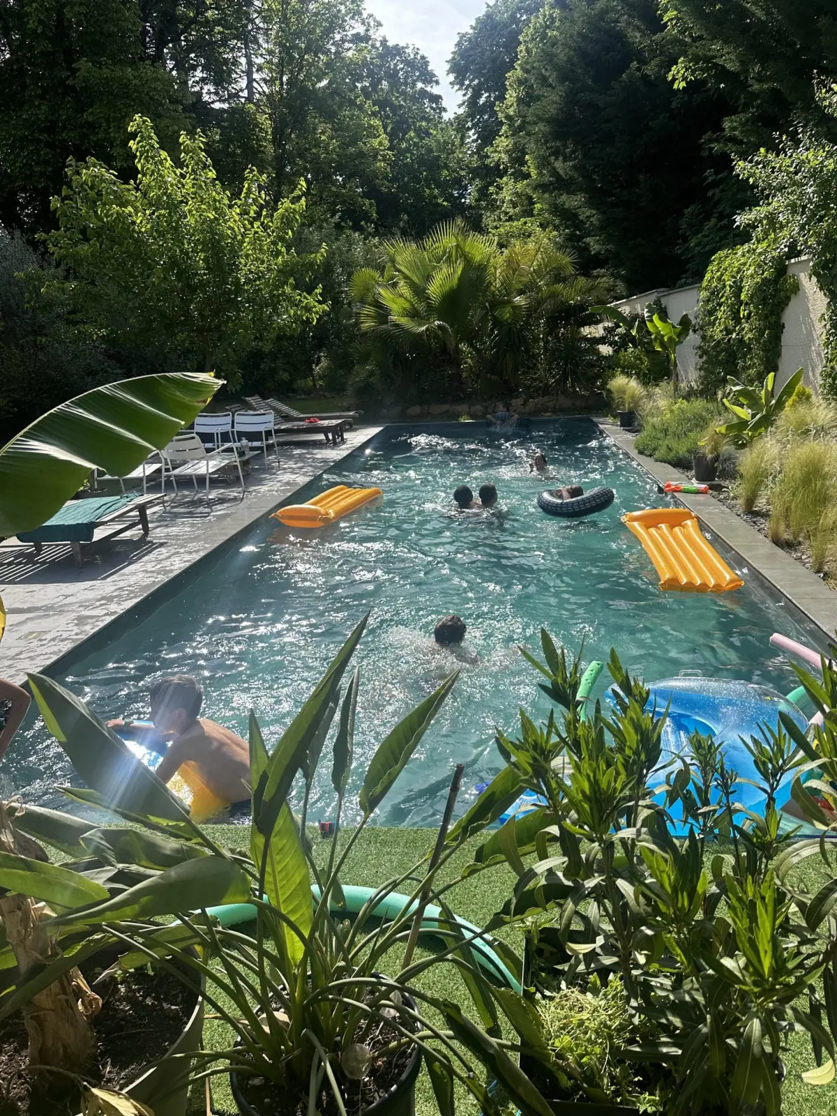 Children swimming with rings and lilos in the Effet Lodge pool surrounded by greenery