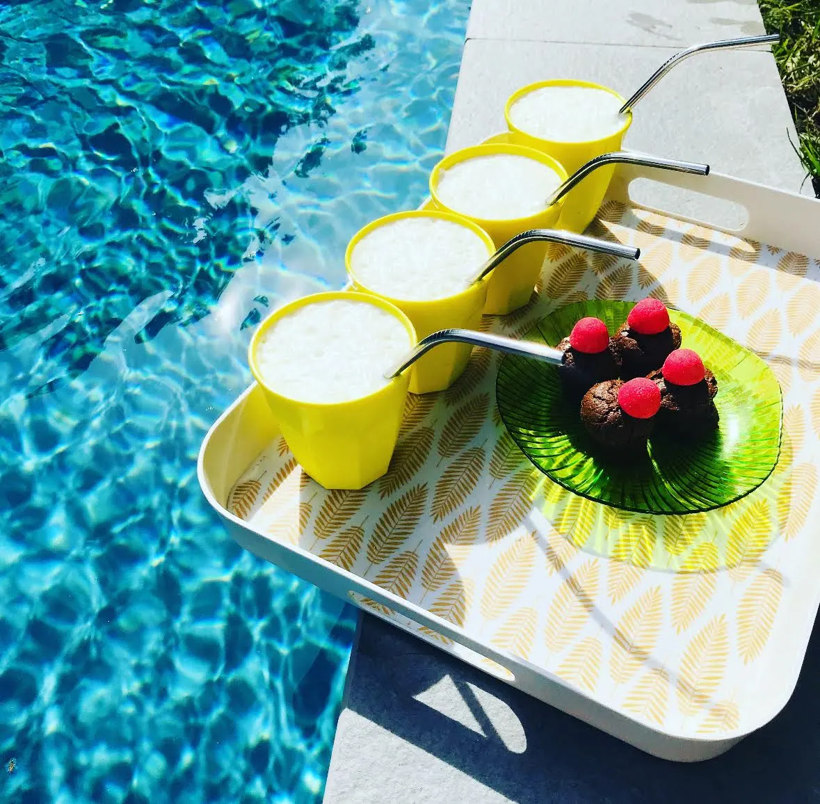 Tray by the Effet Lodge pool: yellow tumblers with steel straws and small chocolate cakes