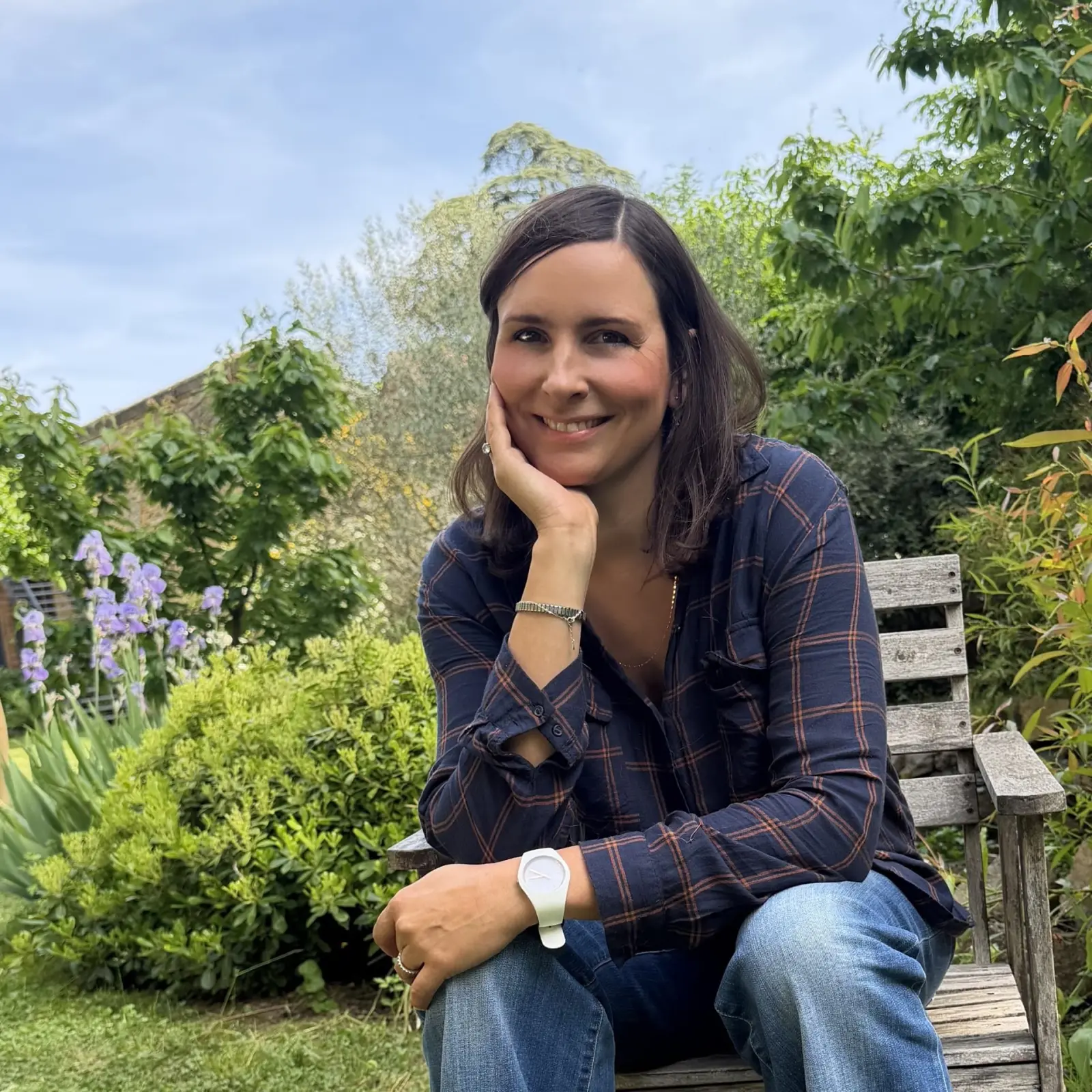 Stéphanie, host of Effet Lodge, smiling as she sits on a wooden bench in the garden