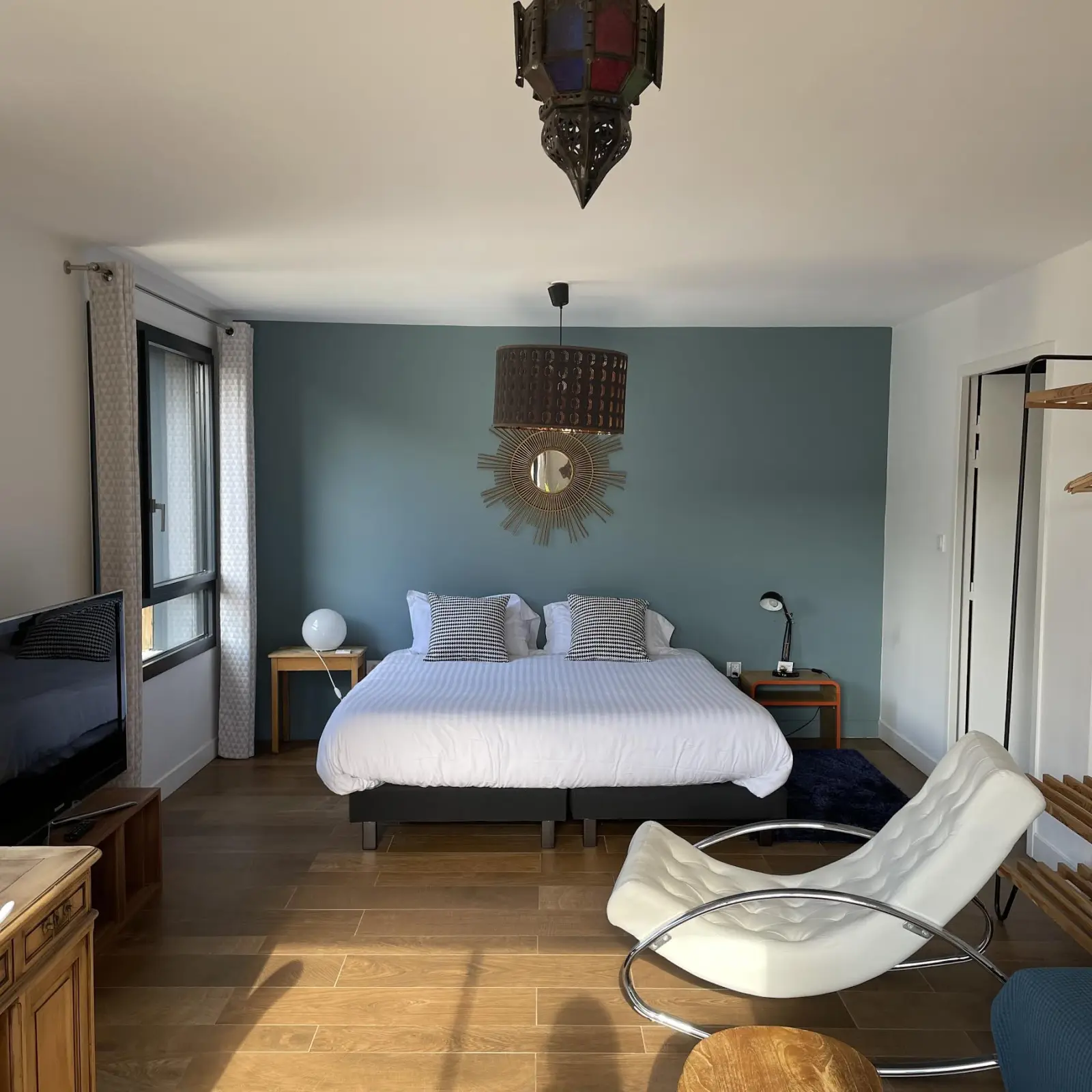 Suite at Effet Lodge: double bed, blue wall, sunburst mirror, white rocking chair and lantern
