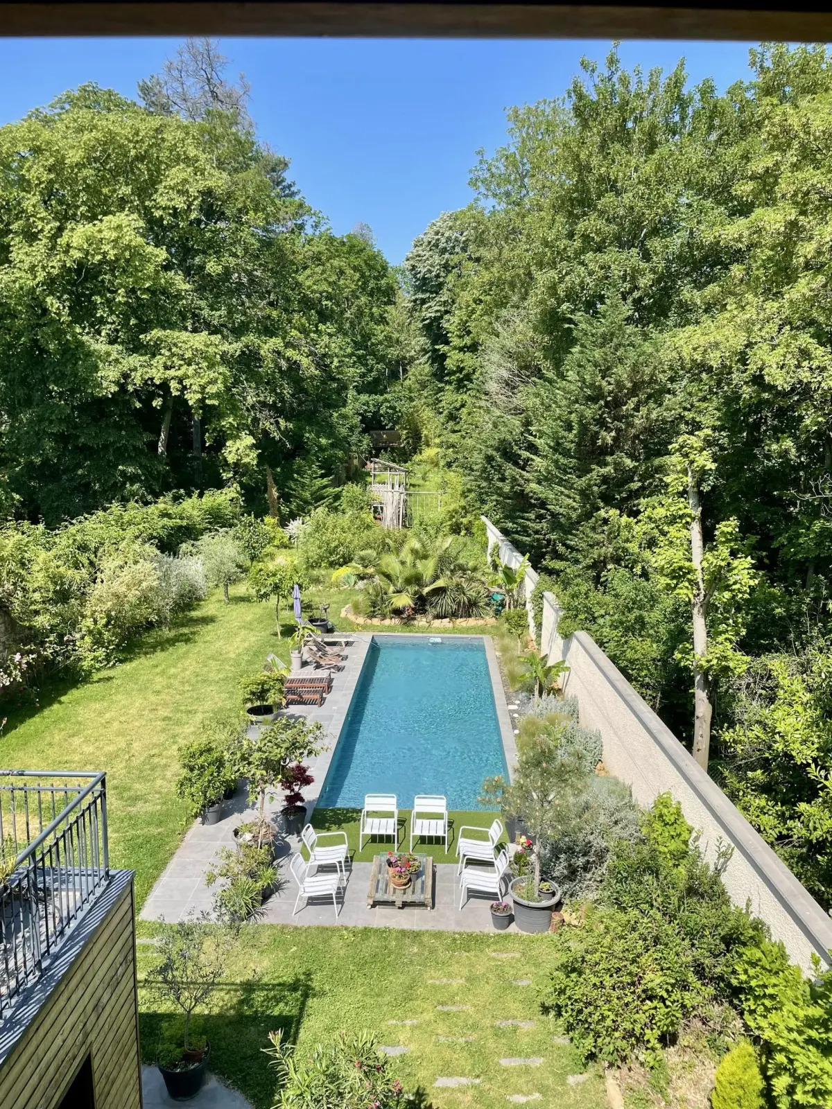 Bird's-eye view of the Effet Lodge garden: rectangular pool, white chairs and tall trees