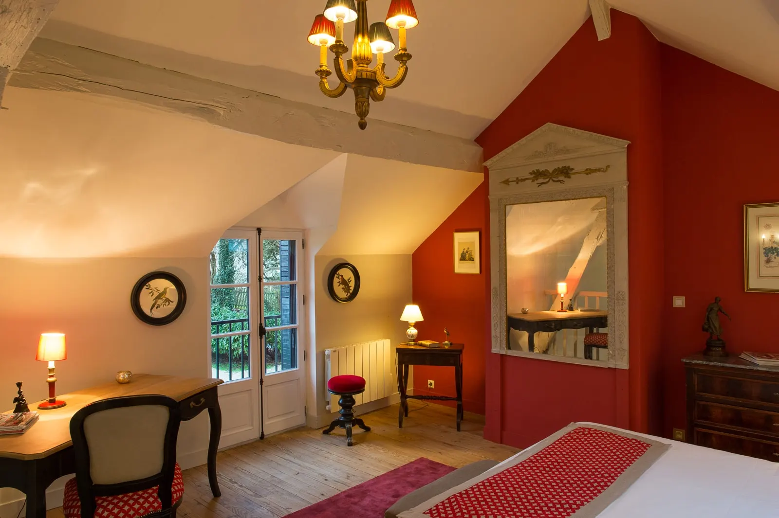 Bedroom under the beams with a desk, French window, red stool and large mirror, La Folie Saint Julien