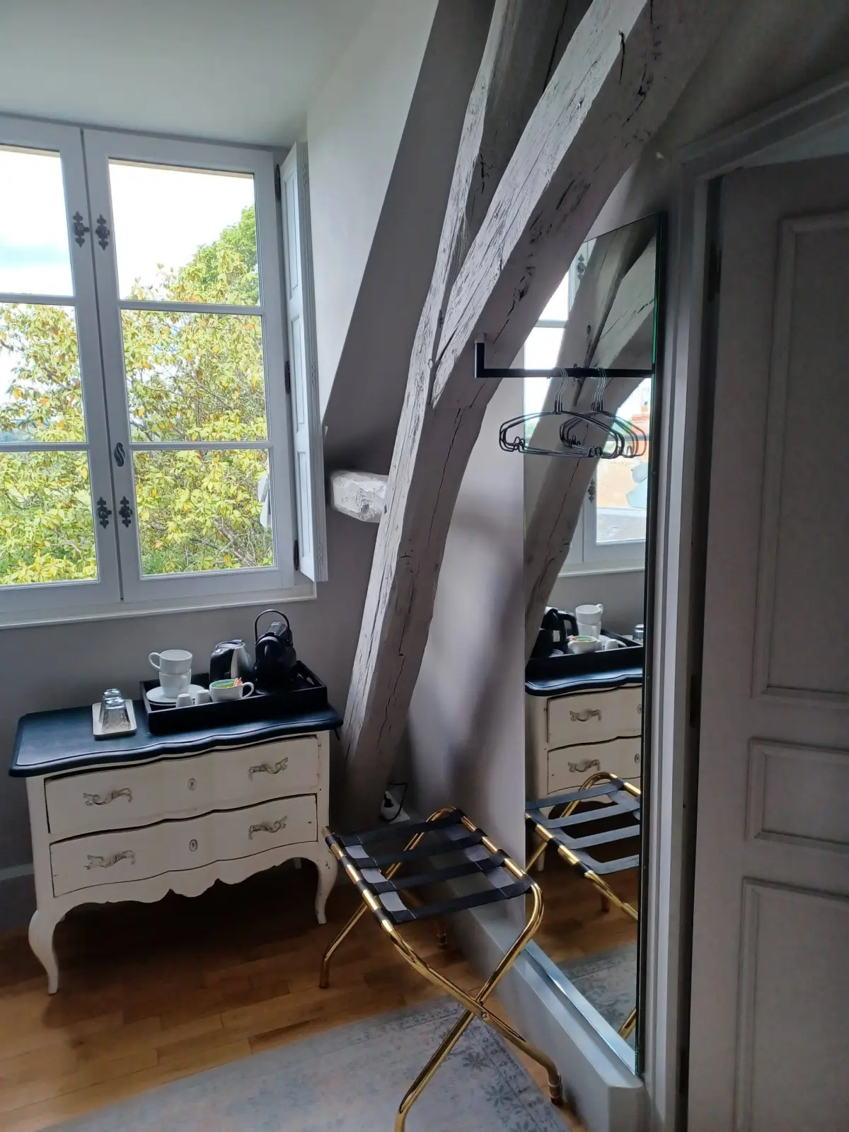 White chest with a tea tray and kettle beneath a window, a beam and a luggage rack, La Folie Saint Julien