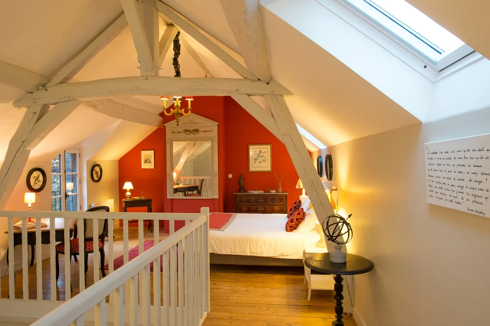 Attic bedroom with whitewashed beams, a red wall, a large mirror and white banister, La Folie Saint Julien
