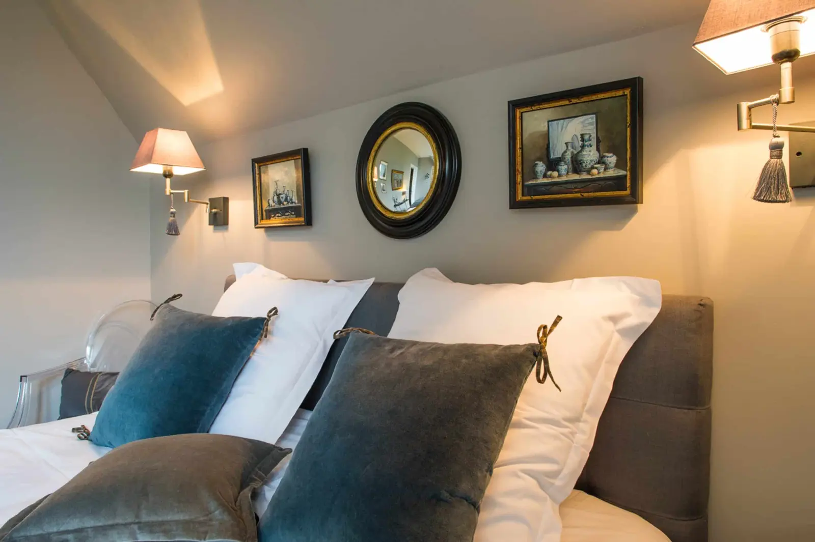 Blue velvet cushions, grey headboard, round mirror and framed still lifes, La Folie Saint Julien