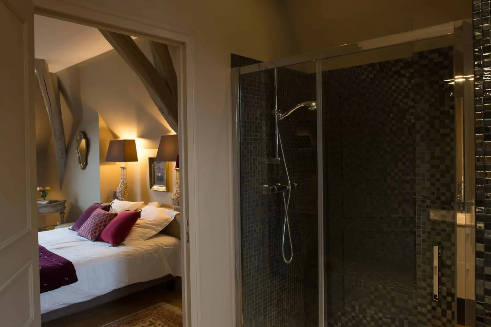 Glass shower with dark mosaic tiles and a door open onto the bedroom under the beams, La Folie Saint Julien