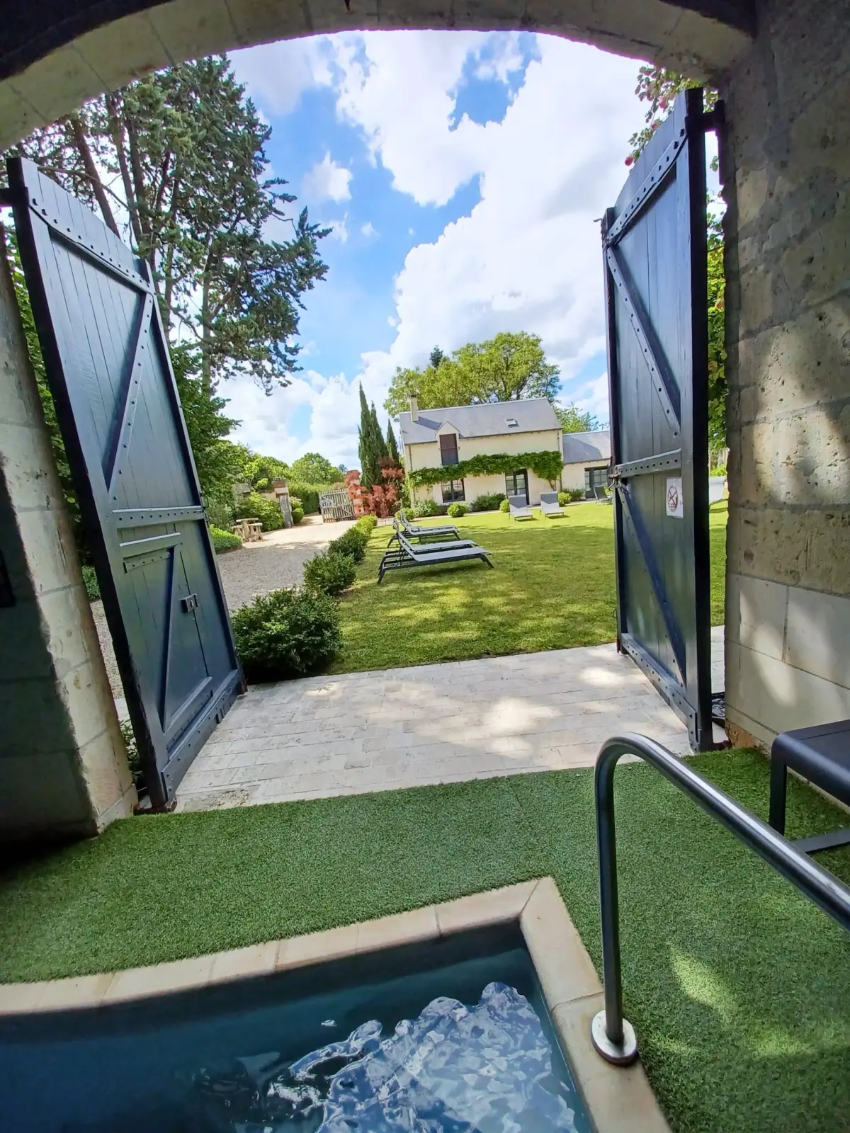 Indoor pool and large doors open onto the garden, its loungers and the house, La Folie Saint Julien
