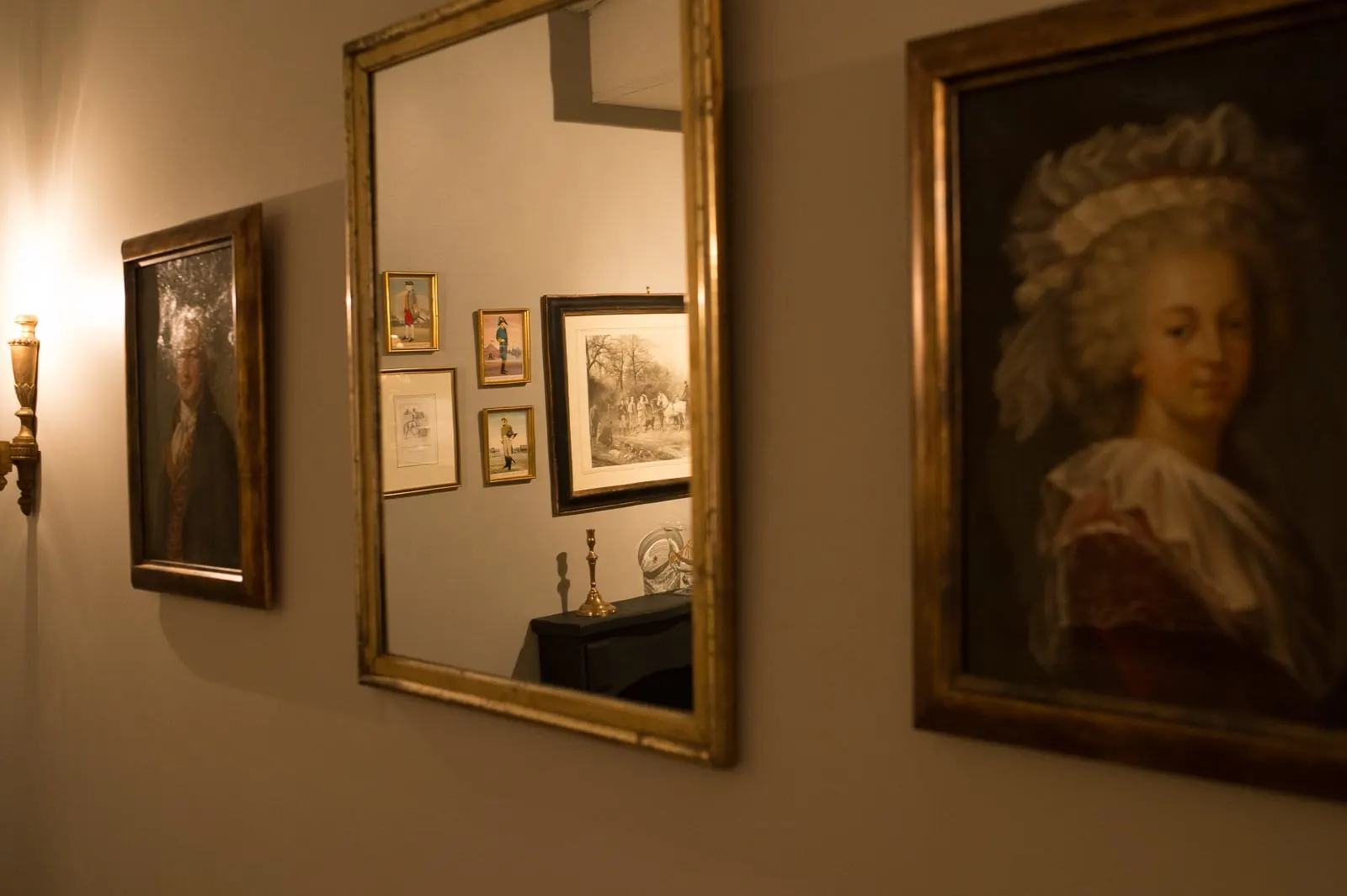 Hallway with gilt-framed old portraits and a mirror reflecting the sitting room, La Folie Saint Julien