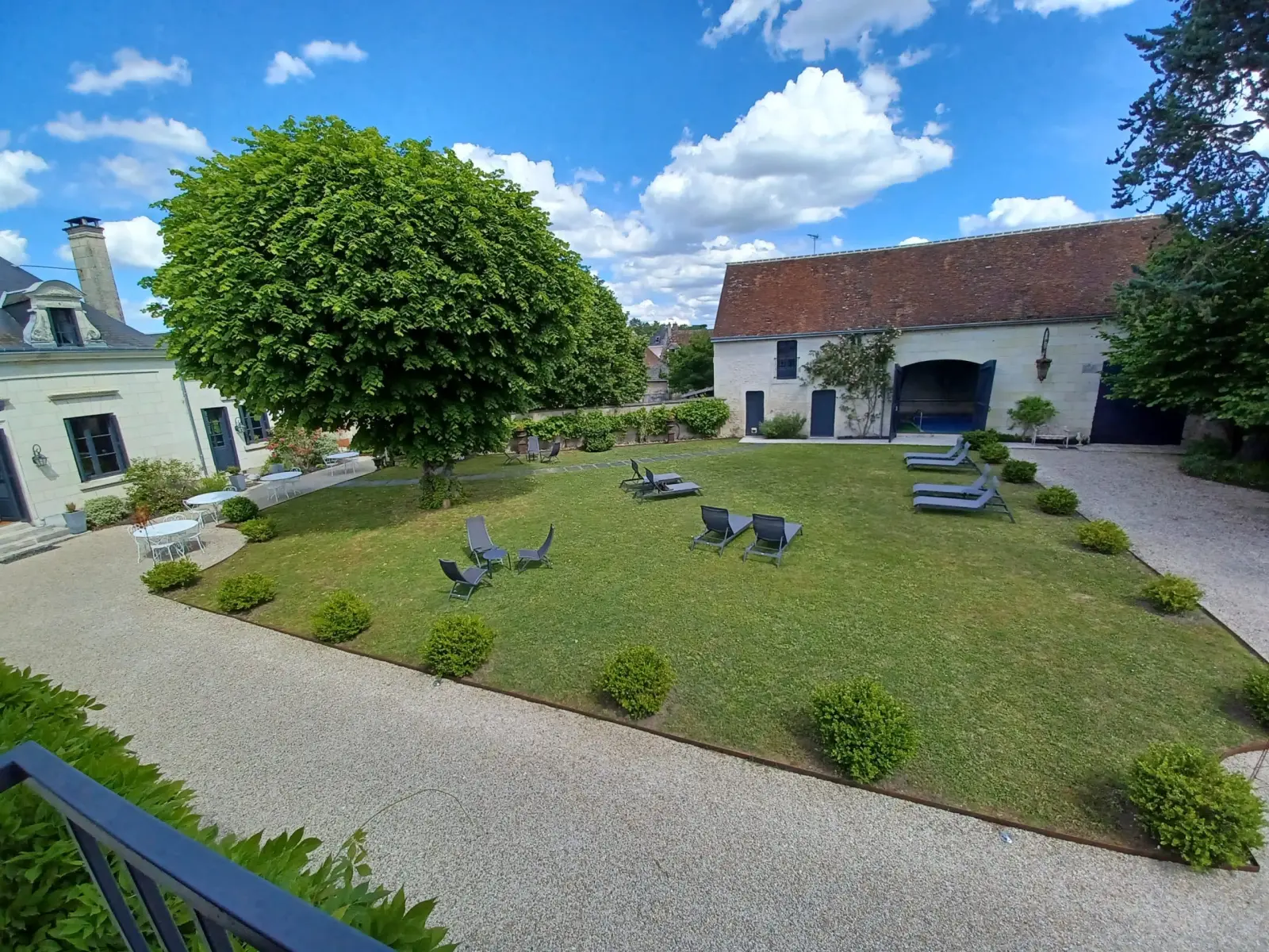 Elevated view of the lawn, large tree, loungers and a stone outbuilding, La Folie Saint Julien