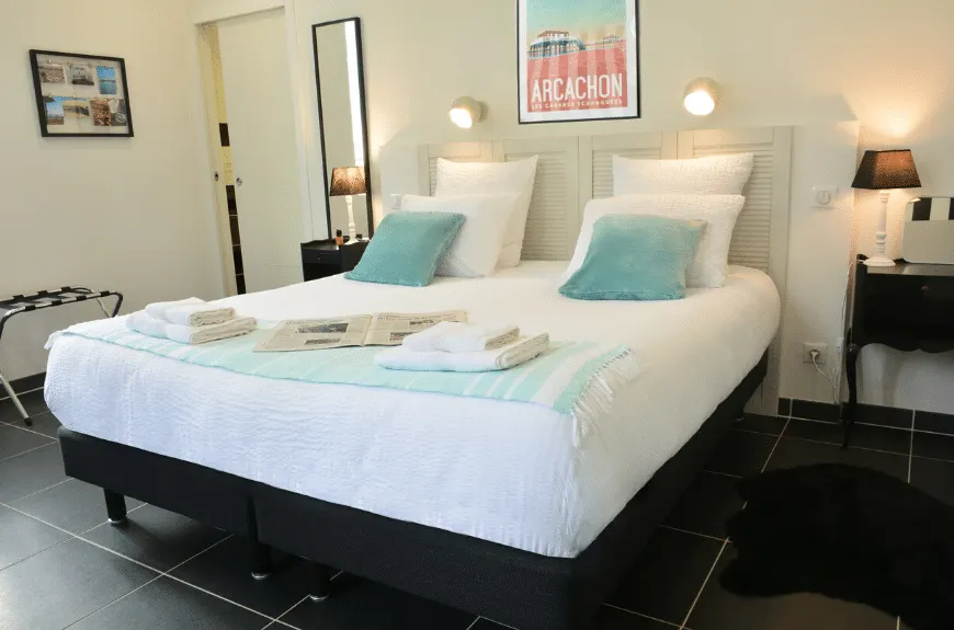 Bedroom at Villa Glen Tara with double bed, turquoise cushions and an Arcachon poster above the bed