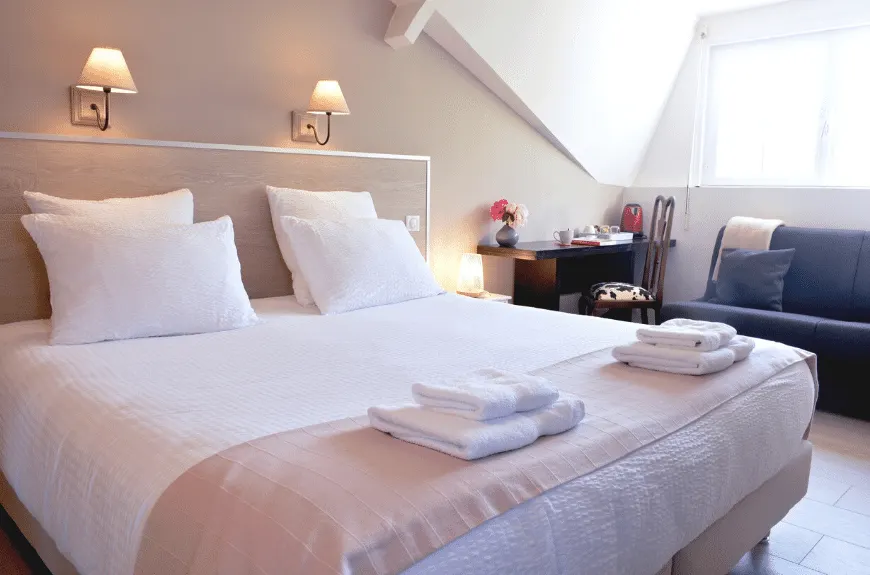 Attic bedroom at Villa Glen Tara: double bed, folded towels, desk and blue sofa