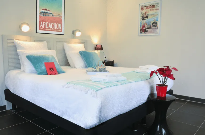 Bedroom at Villa Glen Tara with double bed, turquoise cushions, Arcachon posters and a red poinsettia