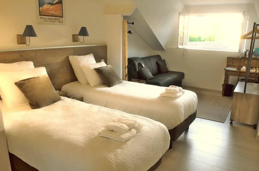 Bedroom at Villa Glen Tara with two single beds, a Pyla-sur-Mer poster and black leather sofa