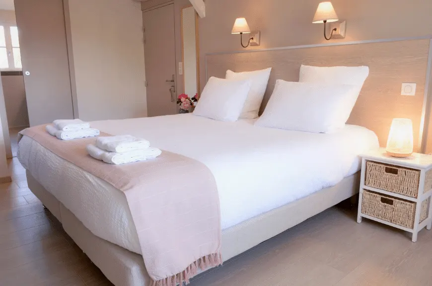 Bedroom at Villa Glen Tara with double bed, white linen, pink throw, wall lamps and wicker bedside table