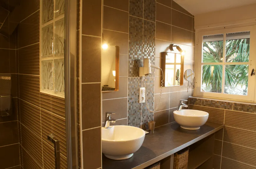 Brown-tiled bathroom with two basins and a window onto a palm tree, Villa Glen Tara