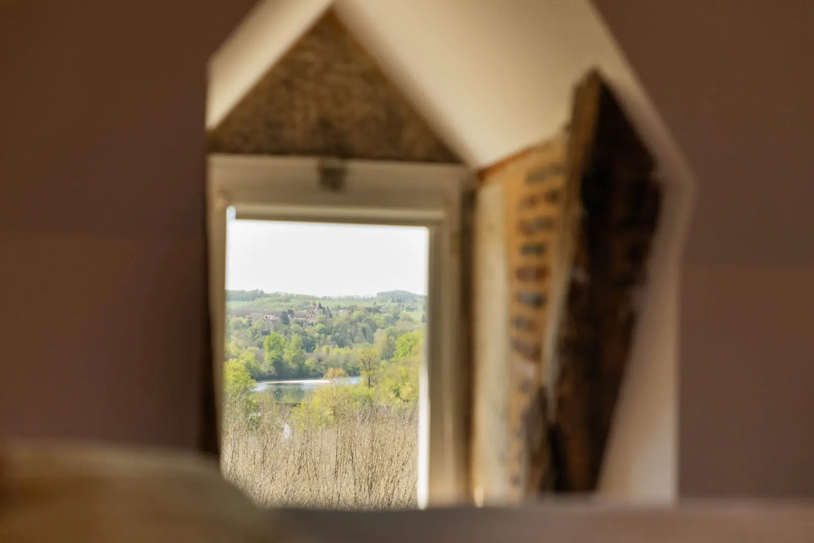 Small window of the Tozeur bedroom at Les Hauts de Saint-Vincent looking out on a green valley and water