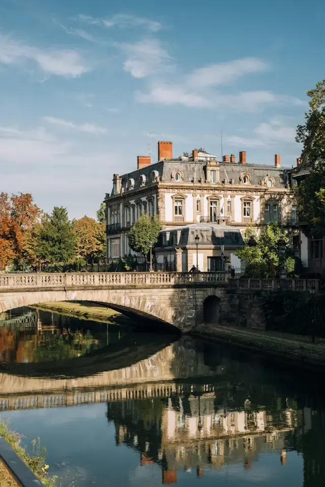 Hôtel particulier aux toits d'ardoise au bord d'une rivière enjambée par un pont de pierre