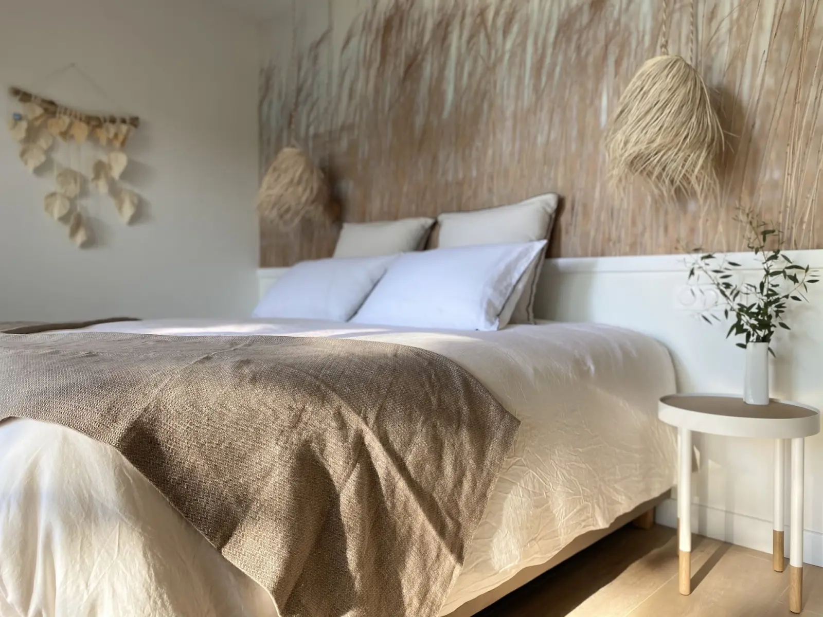 Double room at Kassiopée: white bed, linen throw, dried reed headboard and natural fibre pendants