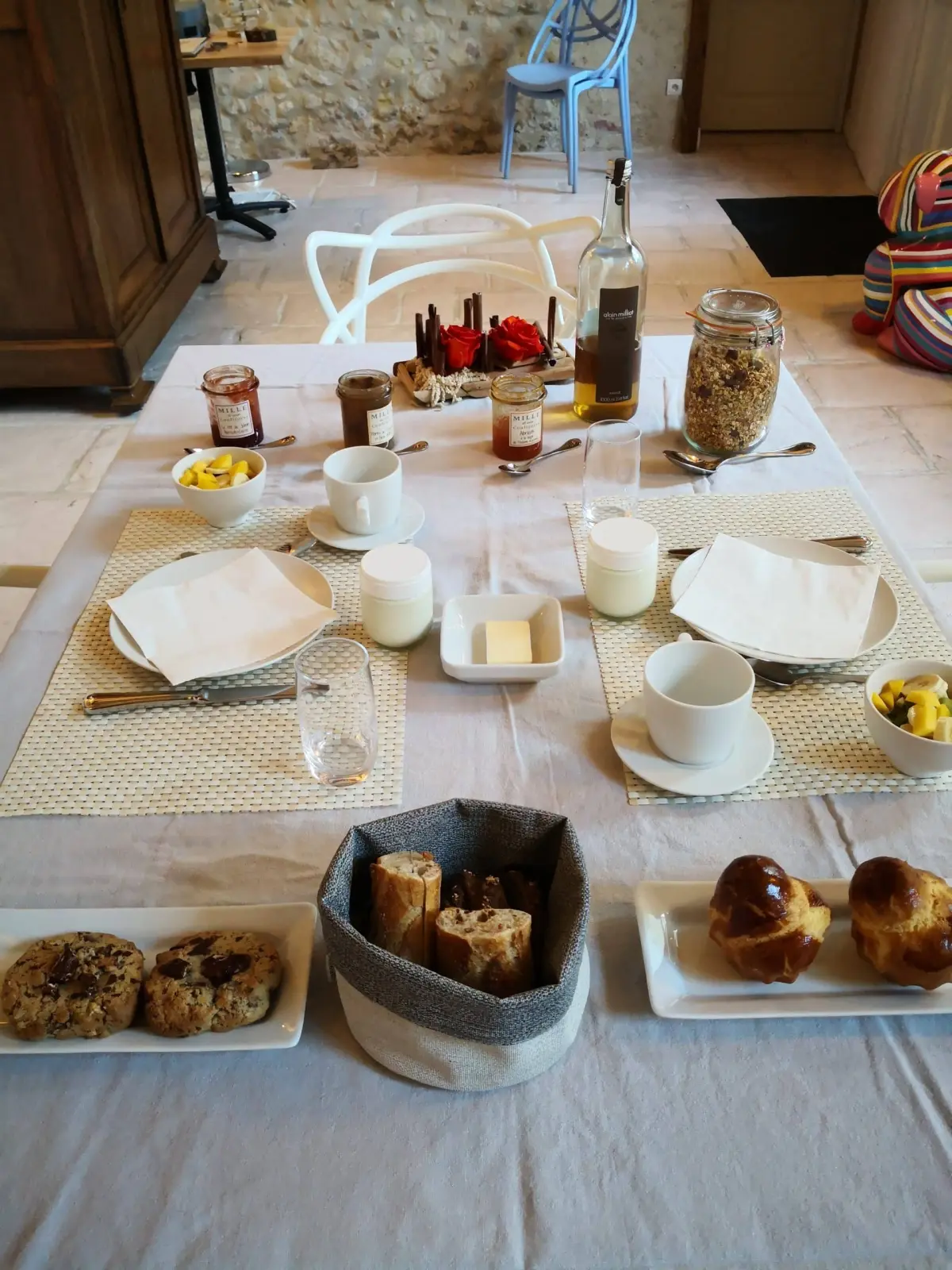 Breakfast table laid with brioches, cookies, jams and granola in a stone-walled room, La Vie Voyage
