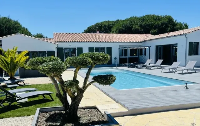 Piscine du 36 devant la maison blanche aux volets verts, olivier taillé et transats