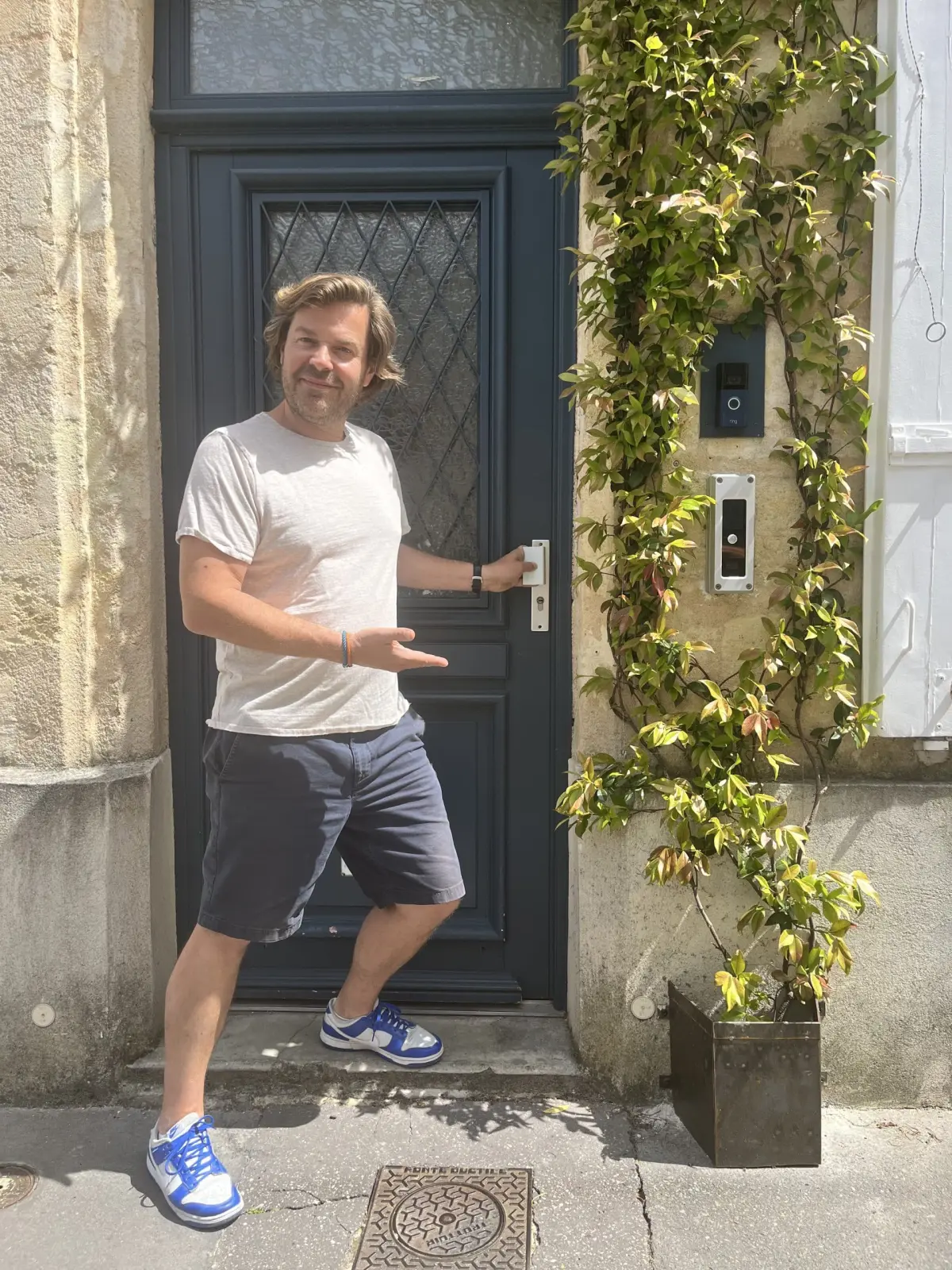 Guillaume, host of Les Séraphines, smiling by the navy front door framed with ivy