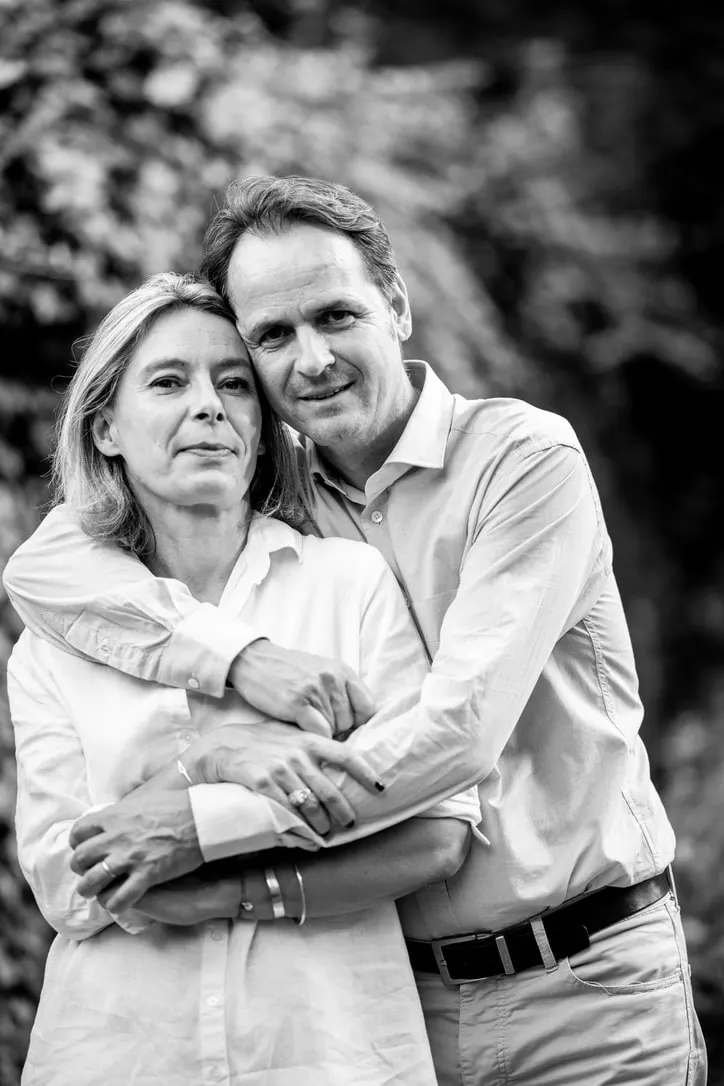 The hosts of La Maison des Monts d'Or embracing, black and white portrait against greenery