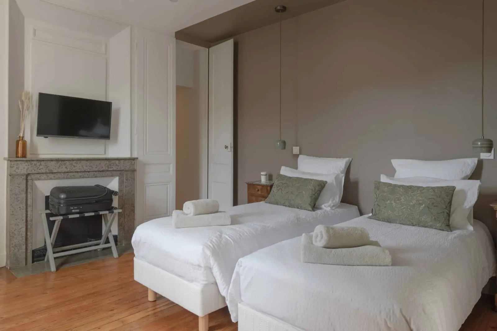 Bedroom at La Maison des Monts d'Or: two single beds, marble fireplace, television and wooden floor