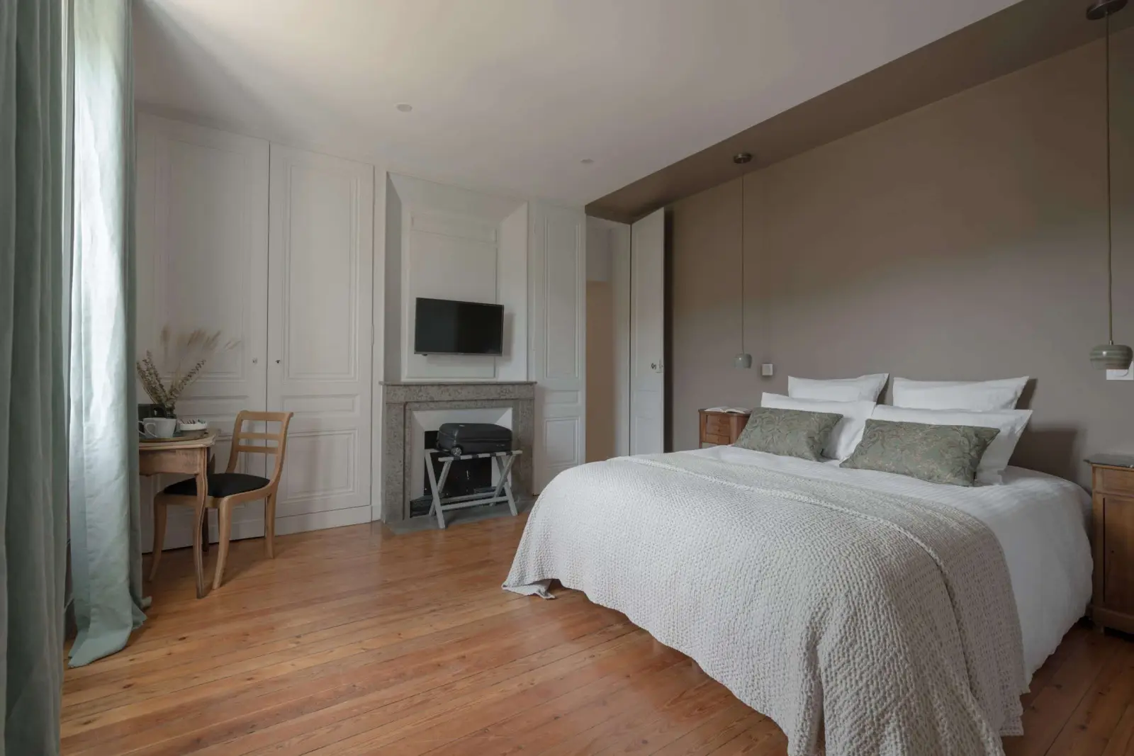 Bedroom at La Maison des Monts d'Or: double bed, marble fireplace, small desk and wooden floor