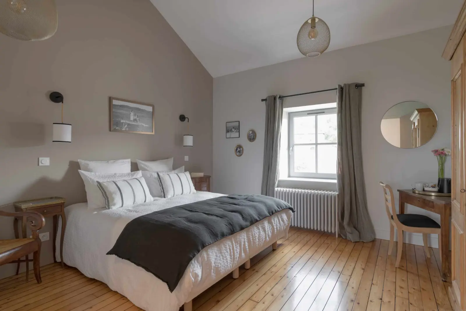 Bedroom with a sloping ceiling at La Maison des Monts d'Or: double bed, wooden floor, desk and grey curtains