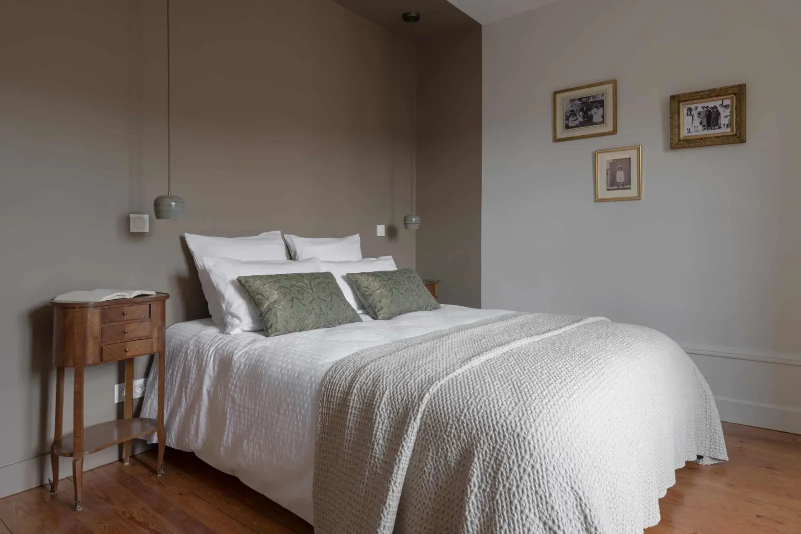 Double bed with green cushions, an antique wooden bedside table and framed photos, La Maison des Monts d'Or
