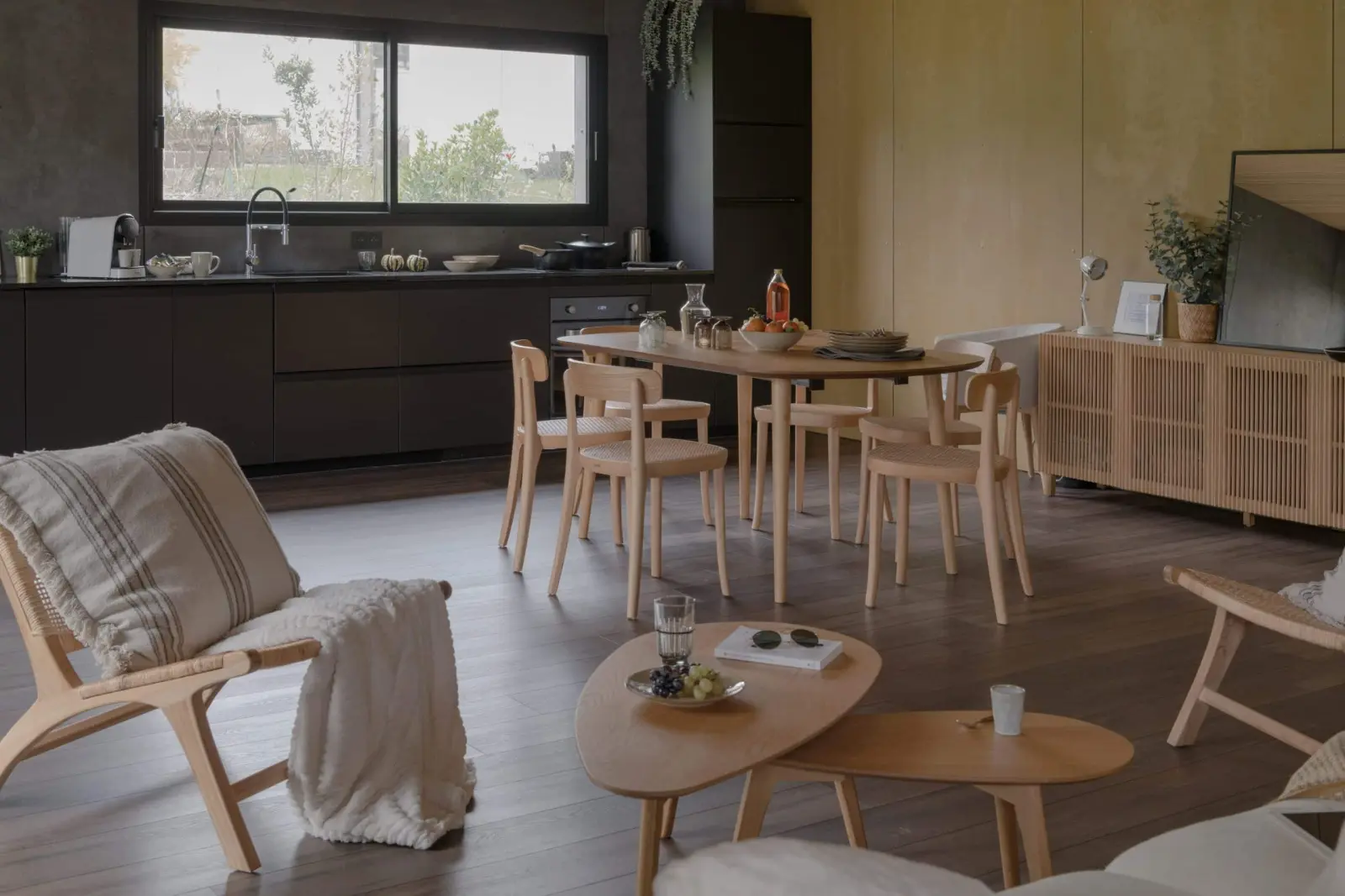 Living area of the gîte with a black kitchen, wooden table and armchairs, La Maison des Monts d'Or