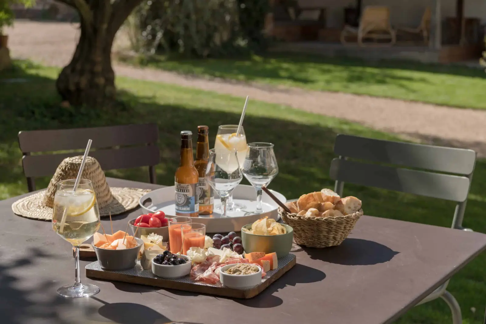 Sharing board, beers, spritz glasses and a bread basket on a table in the grounds, La Maison des Monts d'Or