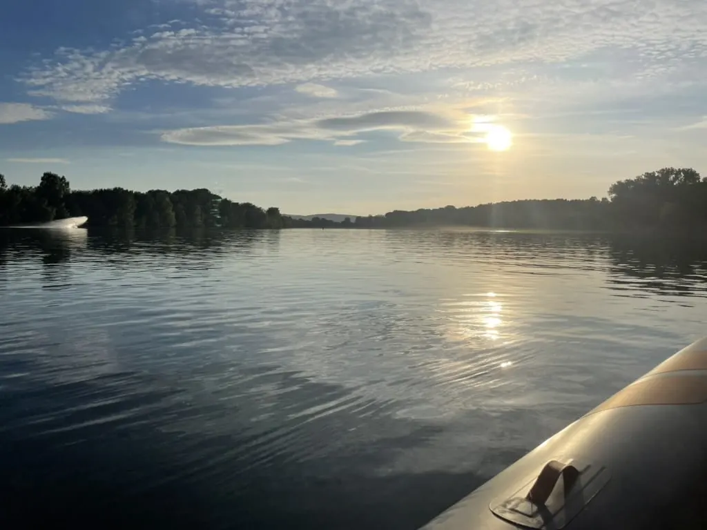 The Saône at sunset seen from a boat, with wooded banks on the horizon, near La Maison des Monts d'Or